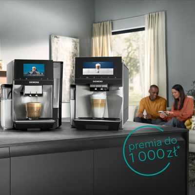 Dwa ekspresy do kawy Siemens na blacie, z parą siedzącą w tle.