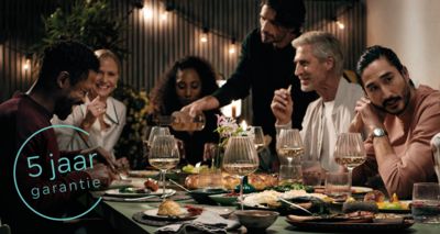 Een familie is aan het dineren aan de eettafel.