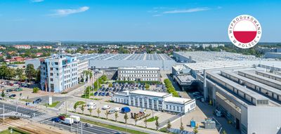 Zdjecie z drona fabryki. Fabryka, zaparkowane auta, las i niebo.