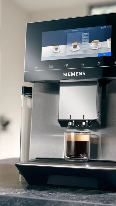 
     Ekspres do kawy Siemens w pełni automatyczny na szarym marmurowym blacie obok cukiernicy.
    