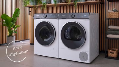 Siemens wasmachine en droger set in moderne wasruimte met houten lattenwerk en groene planten, met "Actie afgelopen" melding in cirkel linksonder 