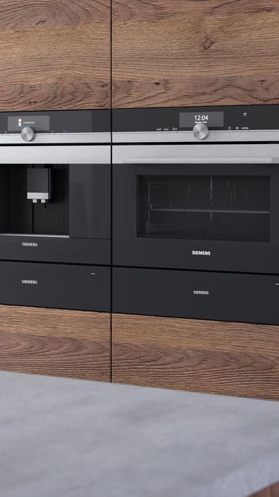 Cocina moderna con horno Siemens empotrado, fregadero de acero, utensilios de madera y decoraci&oacute;n minimalista en tonos madera y verde.