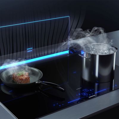 Pans cooking on a hob with steam being extracted