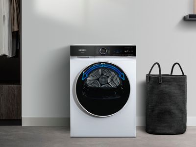 Un sèche-linge Siemens avec une porte noire affichant la fonctionnalité ReversibleDrumPlus et placé à côté d'une armoire remplie de vêtements.