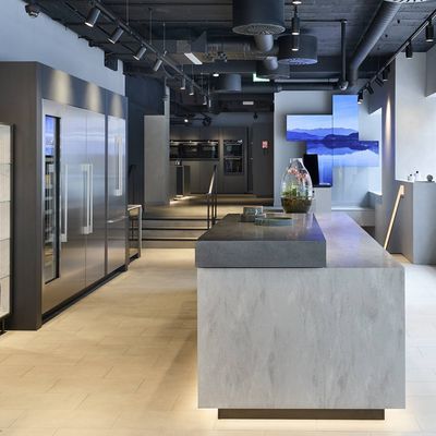 A modern kitchen in a Siemens showroom featuring a large island and a sleek refrigerator. 