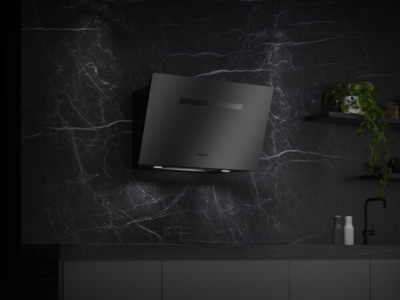Een Siemens wandschouwkap in matte afwerking in een zwarte keuken met zwartmarmer achterwand.