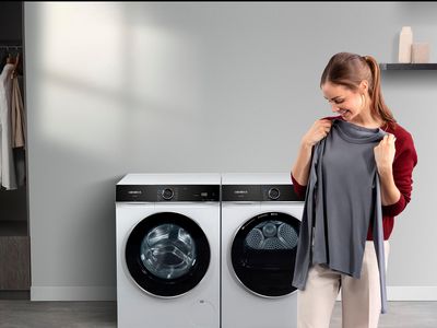 Kobieta trzyma bluzke, w tle pralka i suszarka