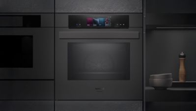 Een slanke zwarte Siemens oven met een digitaal bedieningspaneel boven de glazen deur, naadloos ge&iuml;ntegreerd in een moderne keuken.   