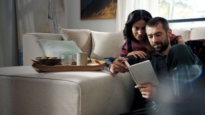 Two people reading a book whilst sat in living area