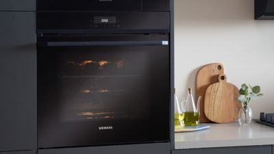 Forno Siemens a exibir p&atilde;o acabado de cozer, real&ccedil;ando uma est&eacute;tica de cozinha elegante com modernidade e efici&ecirc;ncia.
