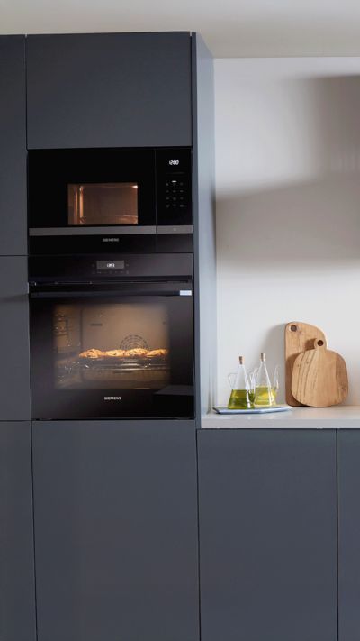 Forno Siemens sofisticado elegantemente integrado, exibindo biscoitos a cozer na perfei&ccedil;&atilde;o numa cozinha elegante.