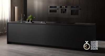 Deze moderne keuken toont een strak zwart kookeiland, een stijlvolle kraan en ingebouwde Siemens ovens tegen een donkere houten wand, terwijl levendige groene planten een verfrissend element toevoegen.