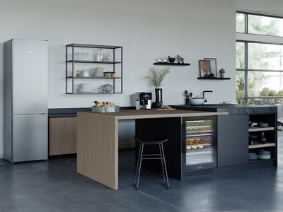 A modern kitchen featuring a spacious island and a sleek refrigerator, showcasing contemporary design elements.  