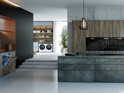A modern open-plan kitchen and laundry area featuring Siemens built-in kitchen appliances, a dishwasher, and two Siemens washing machines