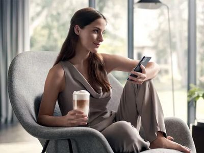 Person sat on chair drinking coffee using app