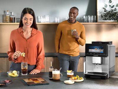 A couple in a modern kitchen making coffee-based cocktails and other coffee drinks with a Siemens coffee machine.