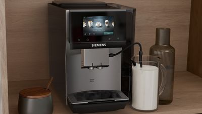 Na pracovn&iacute; desce je elegantn&iacute; k&aacute;vovar Siemens s čerstvou k&aacute;vou.