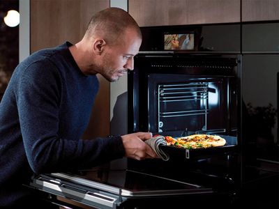 Man taking cooking tray out of oven