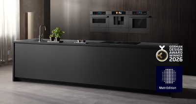 Diese moderne K&uuml;che pr&auml;sentiert eine elegante schwarze Insel, einen stilvollen Wasserhahn und integrierte Siemens Back&ouml;fen, die vor einer dunklen Holzverkleidung platziert sind, w&auml;hrend lebendige gr&uuml;ne Pflanzen einen erfrischenden Akzent setzen.