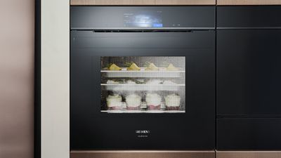 Piekarnik parowy Siemens z dwiema p&oacute;łkami ze szklanymi słoikami i owocami, zamglone okno wskazuje na trwające gotowanie na parze.