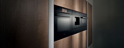Een moderne keuken met ingebouwde zwarte apparatuur tegen een achtergrond van strakke houten kasten. Zachte verlichting benadrukt het elegante ontwerp.