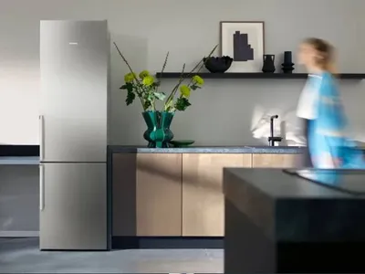 Modernt k&ouml;k med ett kylsk&aring;p i rostfritt st&aring;l, ett i&ouml;gonfallande blomsterarrangemang och str&ouml;mlinjeformade sk&aring;p som skapar en stilfull och inbjudande atmosf&auml;r.