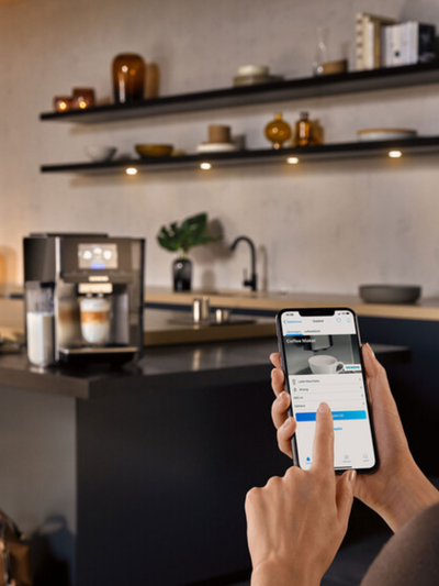 A person viewing the interior of their refrigerator on a smartphone app, showing various food items.