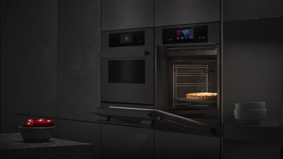 In questa cucina, diversi eleganti elettrodomestici Siemens di colore nero sono integrati in una parete testurizzata e illuminati da un elemento di design.