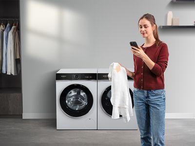 A man with curly hair and a beard sitting on a sofa, looking at his smartphone.
