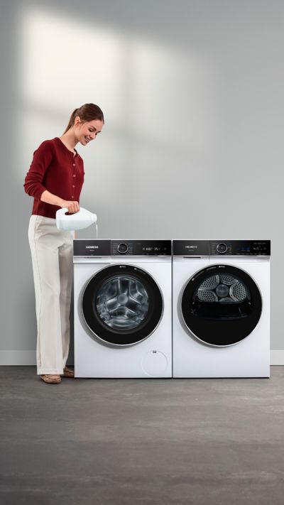 Ein Mann gibt Fl&uuml;ssigwaschmittel in das entsprechende Fach seiner Waschmaschine mit Dosierautomatik.