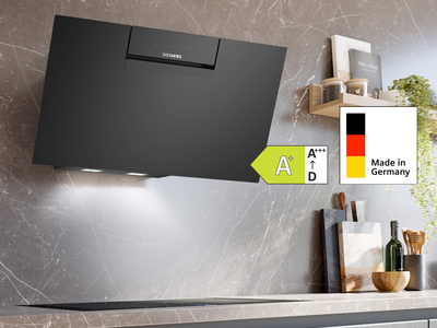 Eine elegante schwarze Dunstabzugshaube an einer Marmorwand mit Effizienzangaben und einer Digitalanzeige auf einem Tablet auf der Arbeitsplatte in der N&auml;he.