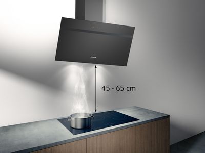 Nowoczesna kuchnia z czarnym okapem ściennym nad garnkiem na płycie indukcyjnej.