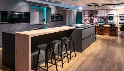 Cucina moderna, elegante con elettrodomestici in acciaio inox, armadi bianchi e grandi finestre.