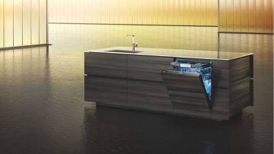 Cucina moderna con isola in legno, lavello integrato e lavastoviglie da incasso parzialmente aperta