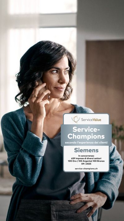 Donna sorridente in un cardigan blu che parla al telefono in una casa elegante.