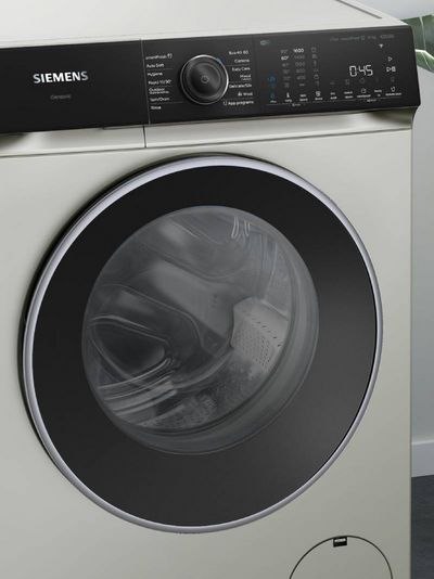 A close-up of a white Siemens iSensoric washing machine with a black control panel displaying various wash programs and a digital timer set to 0:45.