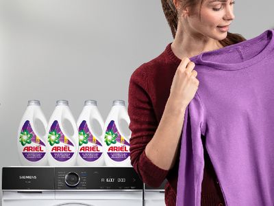 Waschmaschine mit Ariel Waschmittel, violettem Shirt und Hinweis &bdquo;4x Ariel Color+ gratis&ldquo;.