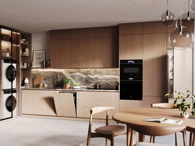 A modern, open-plan kitchen with a large island, integrated Siemens appliances including a hidden laundry area, and a dining space, all featuring sleek, minimalist design.