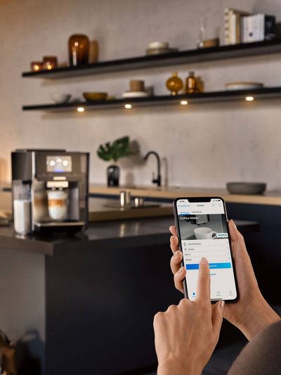 Person using the Home Connect app on their mobile to sync with their coffee machine