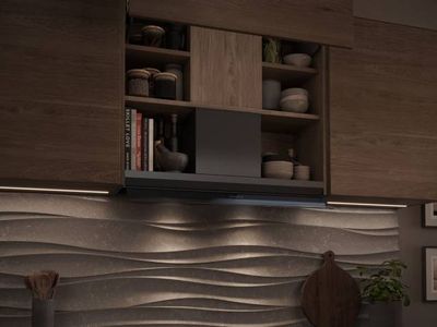 Cuisine moderne en bois avec &eacute;tag&egrave;res ouvertes contenant bocaux et vaisselle, hotte encastr&eacute;e au-dessus d&rsquo;une plaque &agrave; induction, cr&eacute;dence textur&eacute;e en vagues &eacute;clair&eacute;e, ustensiles en bois et plante en pot.