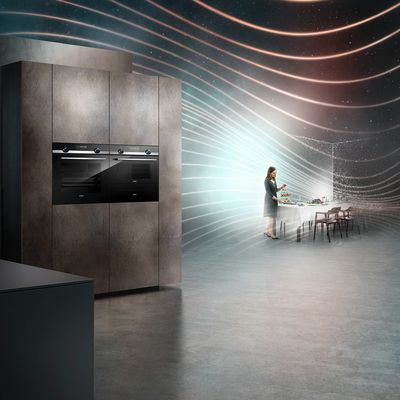 iQ500 ovens in open kitchen with woman preparing for a meal in background