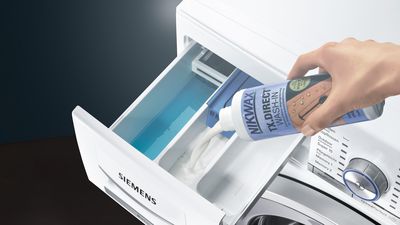 Nahaufnahme wie eine Siemens Waschmaschine mit speziellem Waschmittel für Sportkleidung befüllt wird