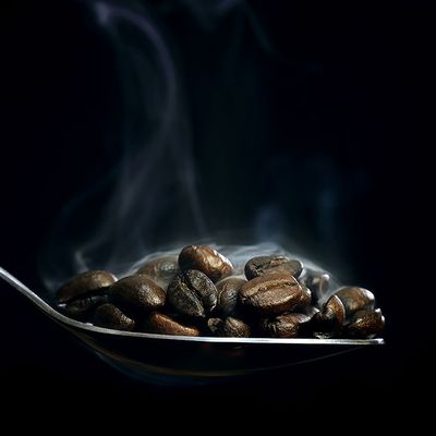 Frisch geröstete Kaffeebohnen auf einem Löffel dampfen noch vor Hitze