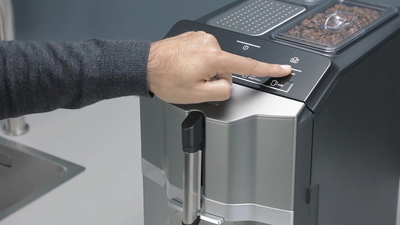 Un doigt tapote dans le réglage du programme calc'n clean d'une machine à café EQ300.