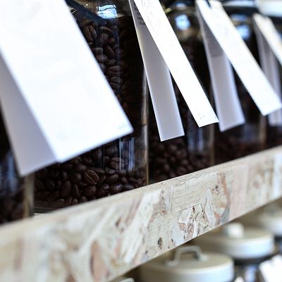 Kaffeebohnen in luftdicht verschlossenen Aufbewahrungsgläsern werden auf einem Holzregal gelagert
