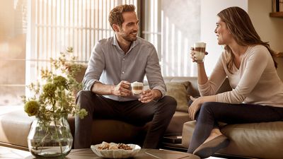 Zwei Personen sitzen auf einer Couch und trinken Kaffee