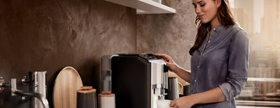 Eine junge Frau macht sich einen Kaffee mit einem Siemens EQ.300 Kaffeevollautomaten