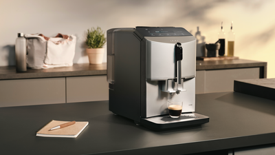 Une machine à café Siemens EQ300 automatique sur un comptoir de cuisine avec deux expressos fraîchement préparés sous la buse d'écoulement du café.