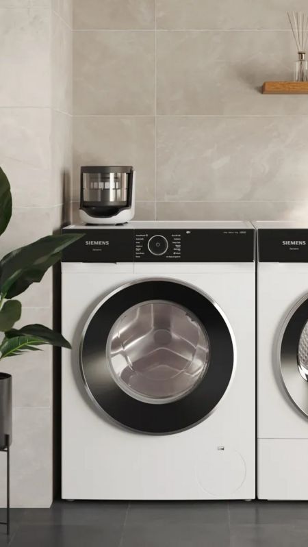 Een vrouw die naast een wasmachine met geïnstalleerd microplastic-filter staat