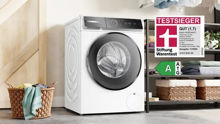 Waschmaschine umgeben von Handtüchern und Ablagen.